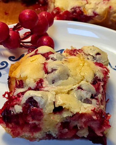 slice of Christmas cranberry cake on a plate with berries