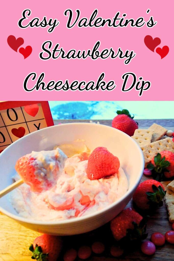 dipping a strawberry into the strawberry cheesecake dip.  strawberries and graham crackers around the bowl